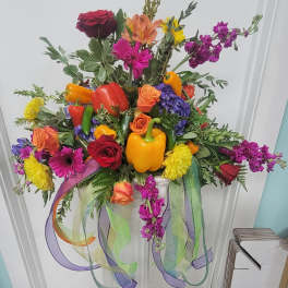 Colorful floral arrangement with peppers and ribbon streamers in a white container