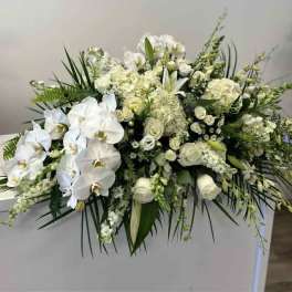 White floral casket spray with orchids and roses