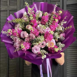 Large bouquet of pink and lavender flowers wrapped in purple paper
