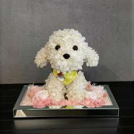 White flower-covered dog figurine in a mirrored tray with pink flowers