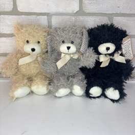 Three plush teddy bears in beige, gray, and black with ribbon bows