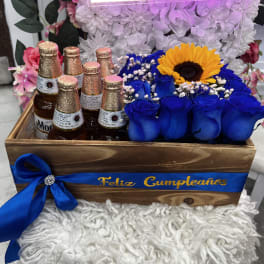 Wooden gift crate with blue roses, a sunflower, and beer bottles
