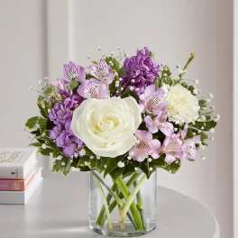 White rose and purple flowers in a clear glass vase