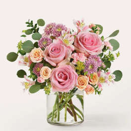 Pink roses and mixed flowers in a clear glass vase