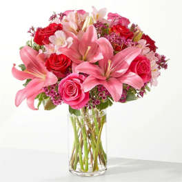 Pink lilies and red roses arranged in a clear glass vase