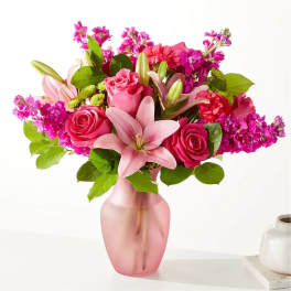 Pink roses and lilies arranged in a frosted pink vase