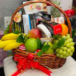 Gift basket with fruit and assorted snack boxes tied with a red ribbon