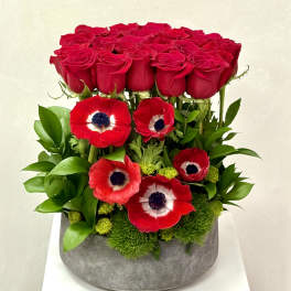 Red roses and red anemones arranged in a gray vase