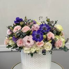 Mixed pink and purple flowers arranged in a white textured vase