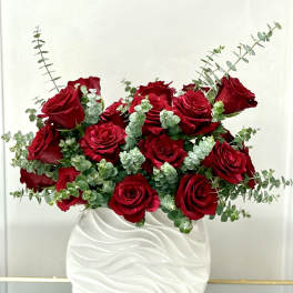 Arrangement of red roses and eucalyptus in a textured white ceramic vase