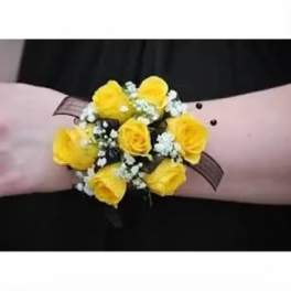 Yellow rose wrist corsage with white filler flowers on a pink band