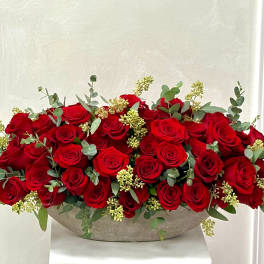 Low arrangement of red roses in a shallow bowl with eucalyptus accents
