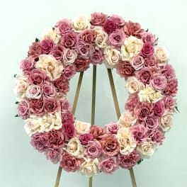 Heart-shaped wreath of pink and cream roses on a wooden easel