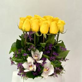 Yellow roses and white orchids arranged in a white vase
