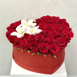 Heart-shaped box filled with red roses and white orchids