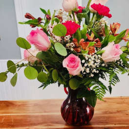 Mixed pink and red roses in a dark glass vase