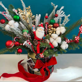 Christmas arrangement with Santa figurine, ornaments, and cotton stems in a plaid container