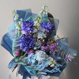 Large bouquet of purple and blue flowers wrapped in blue paper