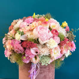 Large pink and peach mixed flower arrangement in a velvet hat box