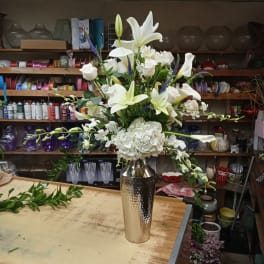 White lilies and roses arranged in a tall silver vase