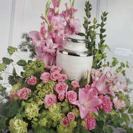 Pink lilies and roses arranged around a white urn