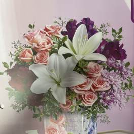 Pink roses, white lilies, and purple flowers in a decorated vase