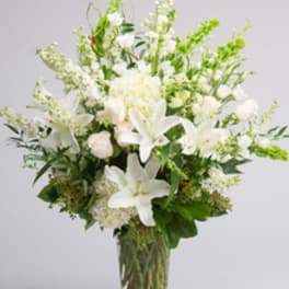 White lilies and pale blooms arranged in a clear glass vase