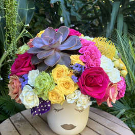 Colorful bouquet with roses and a large succulent in a face vase