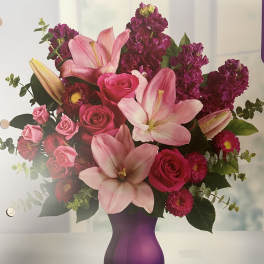 Pink lilies and roses in a purple vase