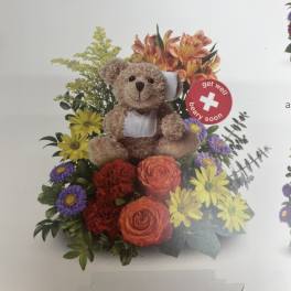 Teddy bear in a colorful flower arrangement with a get well sign