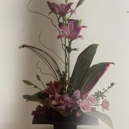 Tall floral arrangement with pink lilies and orchids in a black vase