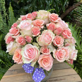 Bouquet of pink roses in a vase with a purple polka-dot ribbon