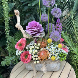 Mixed floral arrangement in a stone container with purple, pink, and white blooms