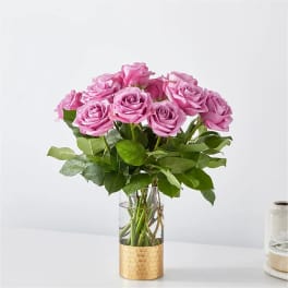 Pink roses arranged in a clear glass vase with a gold base