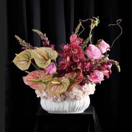 Pink and burgundy floral arrangement in a white vase