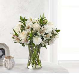 White flowers arranged in a clear glass vase on a table