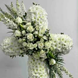 White floral cross on a stand with roses and chrysanthemums