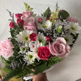 Bouquet of pink roses, carnations, and white daisies wrapped in clear plastic
