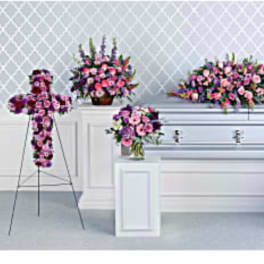 Pink and purple funeral floral sprays around a silver casket