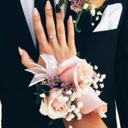 Man in a suit with a rose boutonniere and matching wrist corsage