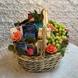 Gift basket with roses, grapes, and assorted chocolates in a wicker basket