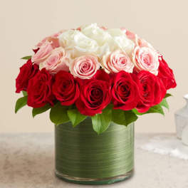 Red and blush roses arranged in a green glass vase