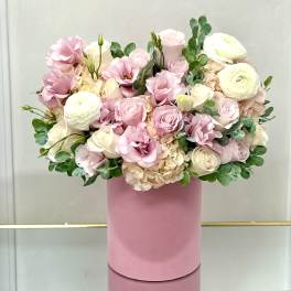 Pink and white roses with ranunculus in a pink hat box