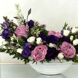 Pink, purple, and white floral arrangement in a white bowl vase