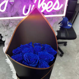 Bouquet of vivid blue roses wrapped in black paper with a blue ribbon