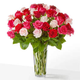 Bouquet of pink, red, and white roses in a clear glass vase