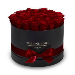 Round box filled with red roses and tied with a red ribbon