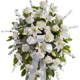 White floral standing spray with lilies, roses, and ribbon