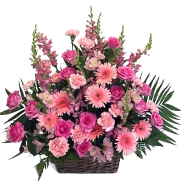 Pink roses, gerbera daisies, and carnations in a wicker basket