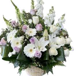 Basket arrangement of white lilies, roses, and daisies with pale lavender roses